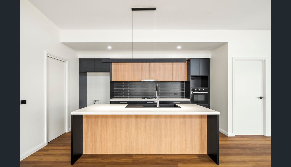 Modern kitchen with light wood cabinets, black accents, and a central island.