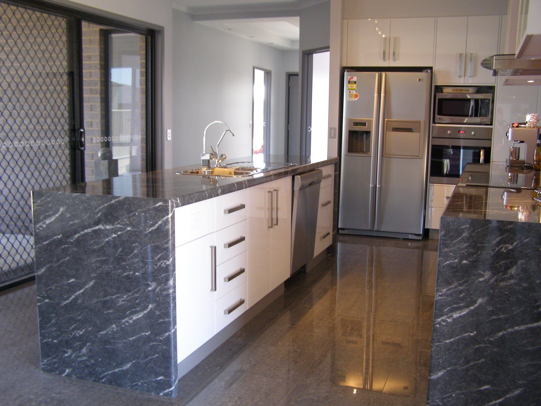 Modern kitchen with white cabinets, stainless steel appliances, and dark granite countertops.