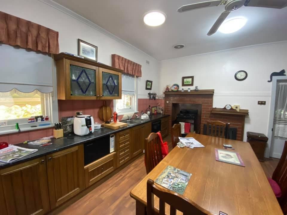 Kitchen with wooden cabinets, countertop, table, and fireplace. Ceiling fan and light fixture.