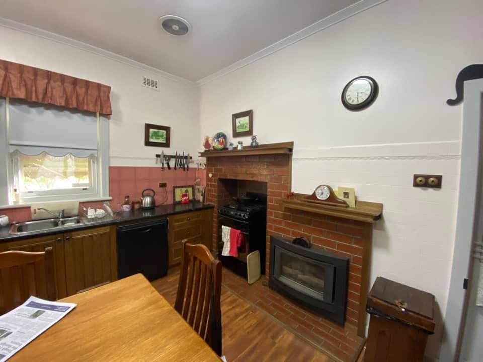 Kitchen with wooden cabinets, black appliances, a brick fireplace, and a wooden table.
