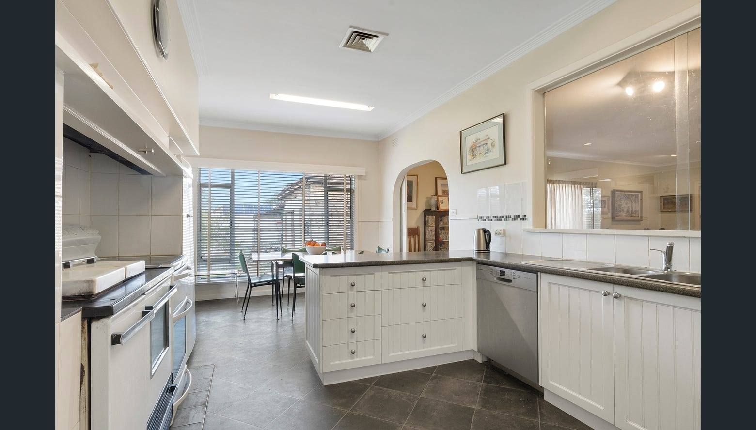 Kitchen with white cabinetry, stainless steel appliances, dark tile floor, and large window.