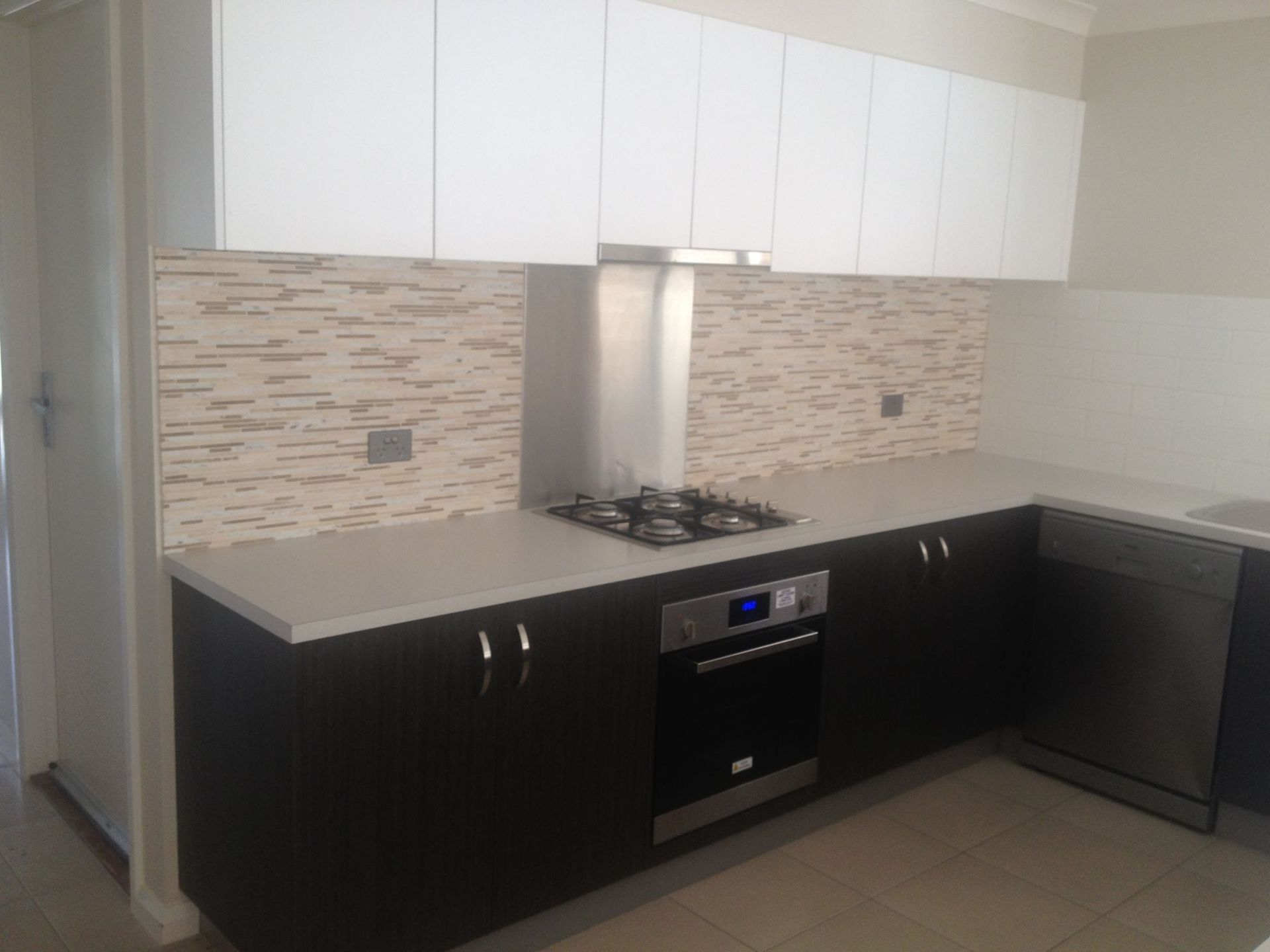 Modern kitchen with white upper cabinets, dark lower cabinets, and a tile backsplash.