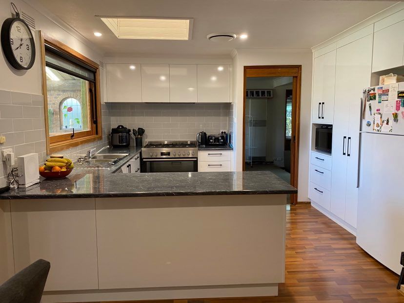 Modern kitchen with white cabinets, dark countertops, and stainless steel appliances.