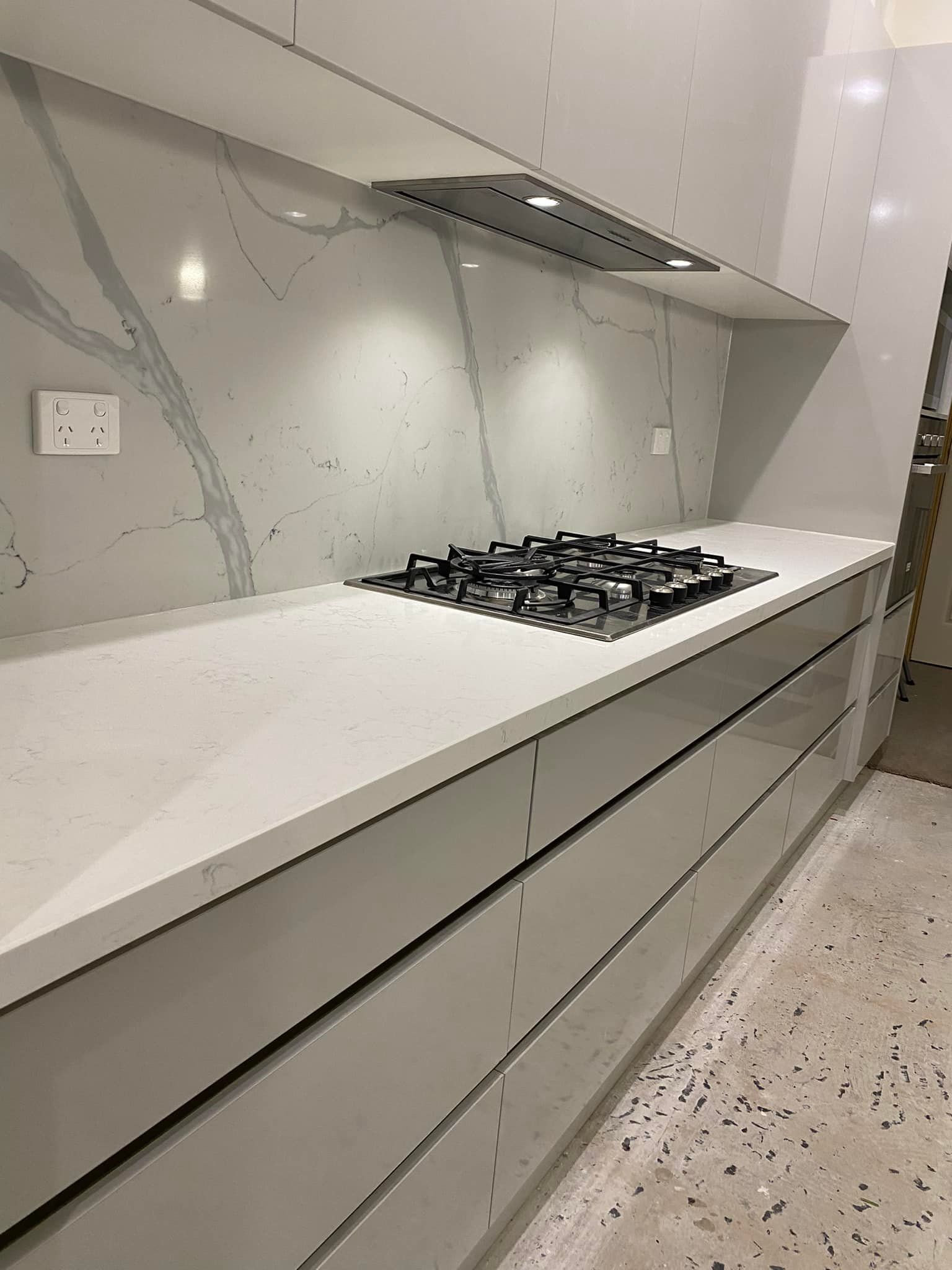 Modern kitchen with white countertops, gas stovetop, and gray cabinets.