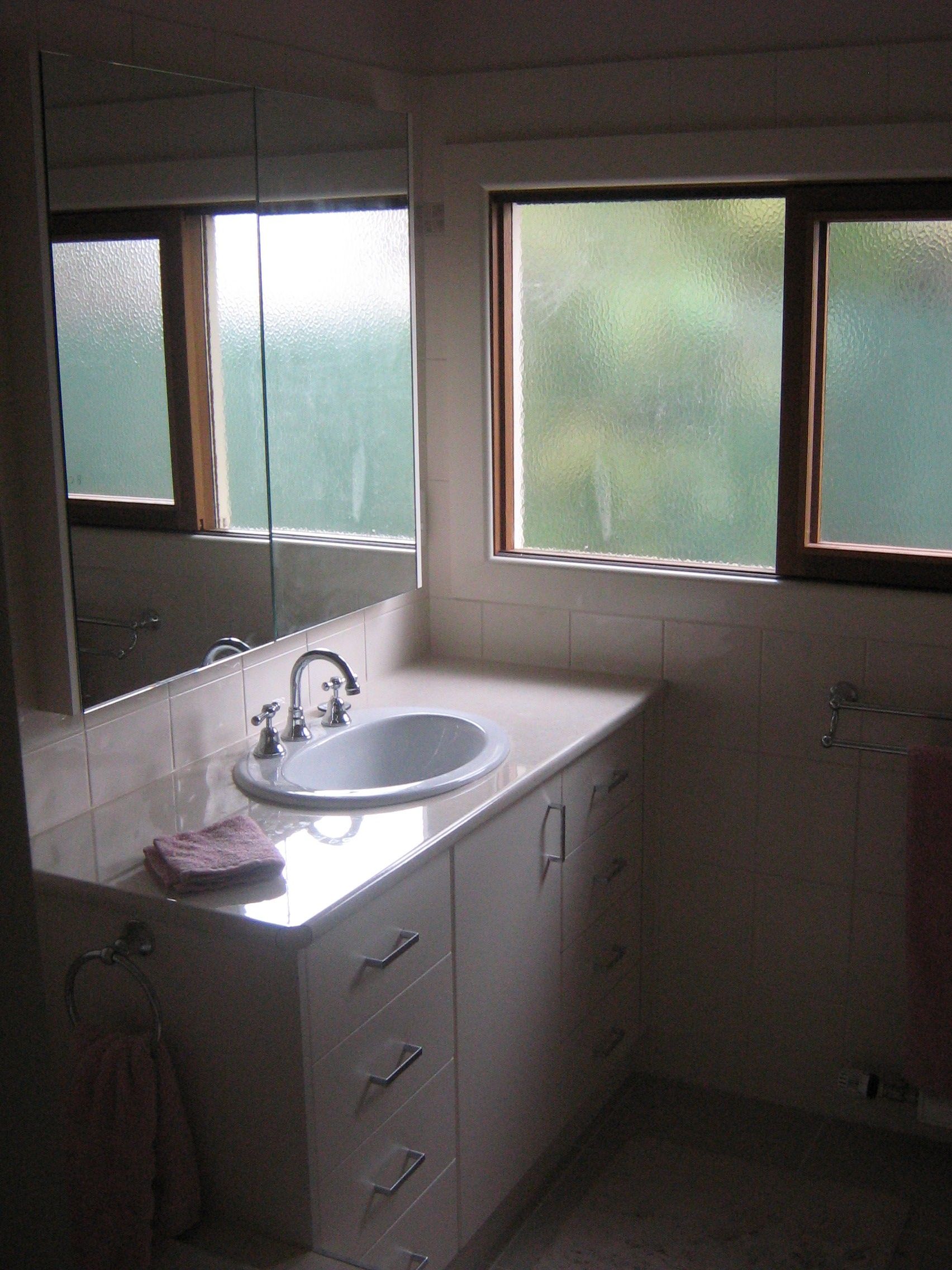 Bathroom with a sink, cabinet, mirror, and windows.