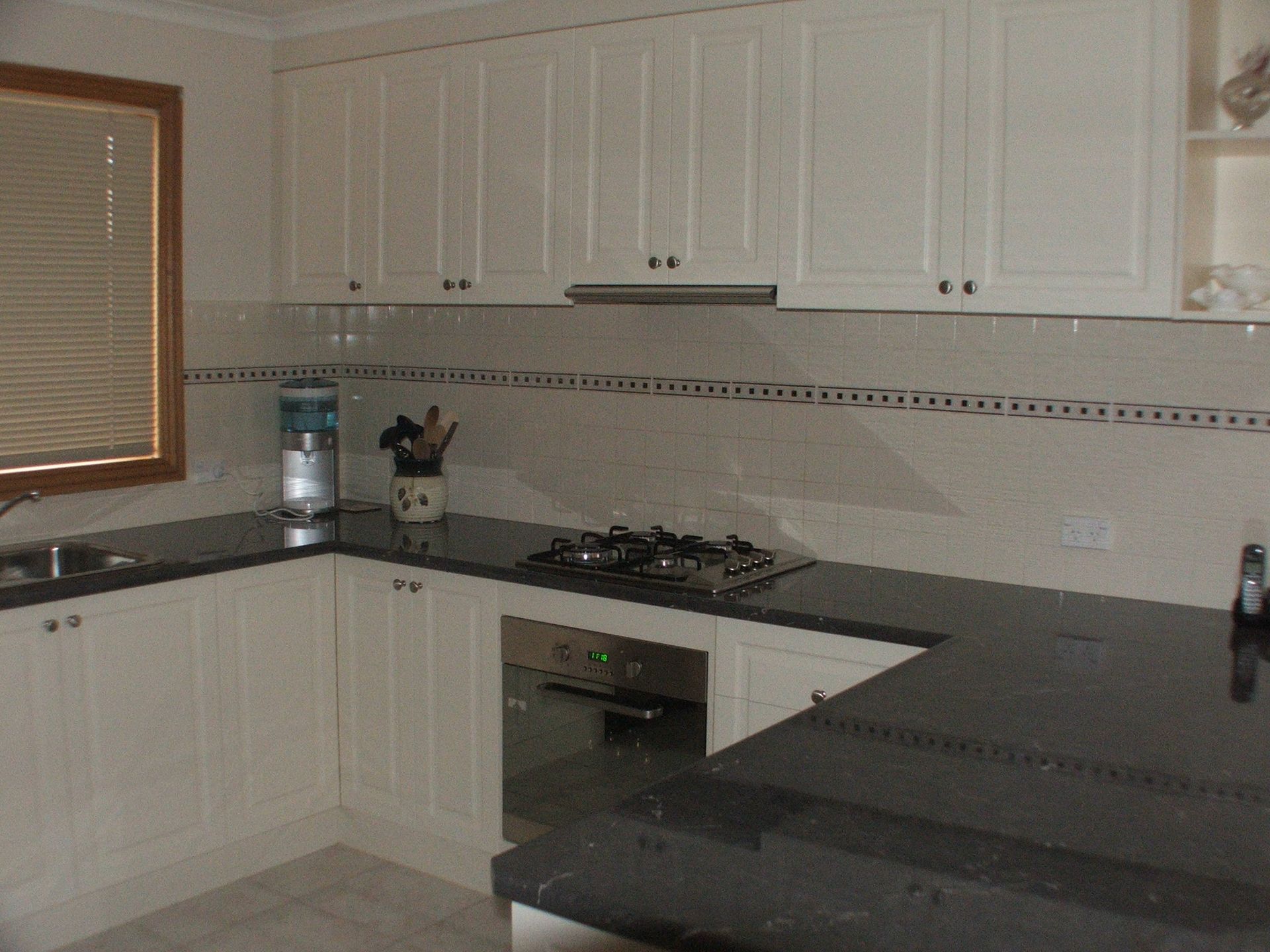 Kitchen with white cabinets, dark countertops, and stainless steel appliances.
