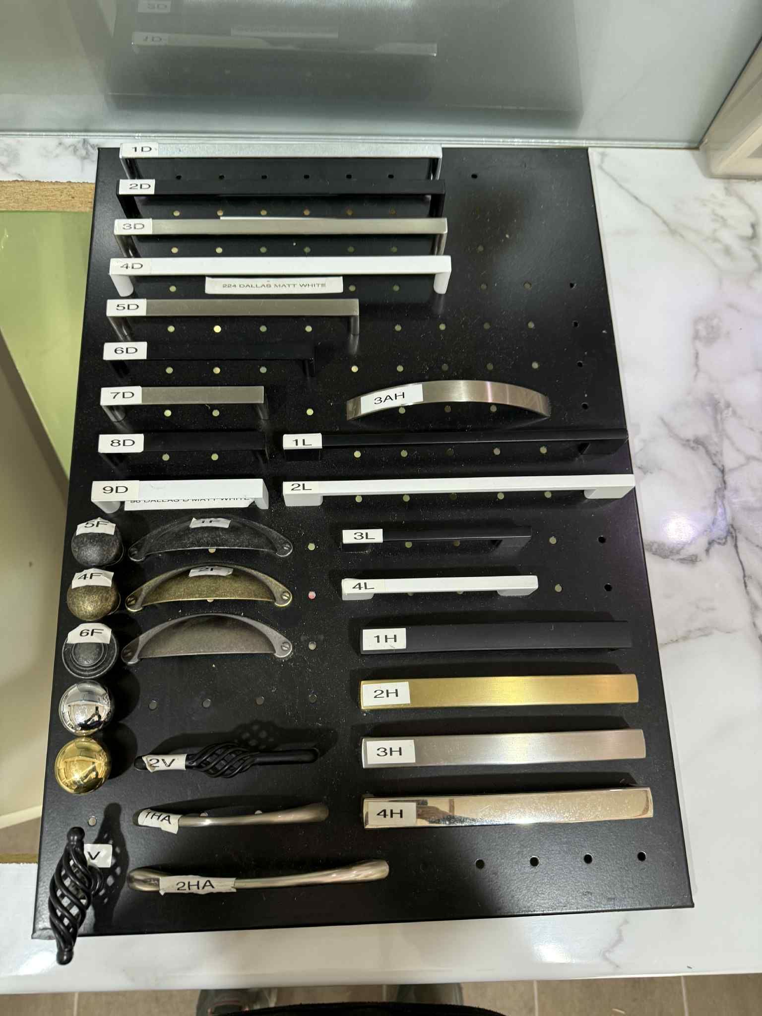 Black display board showcasing various cabinet handles and knobs.