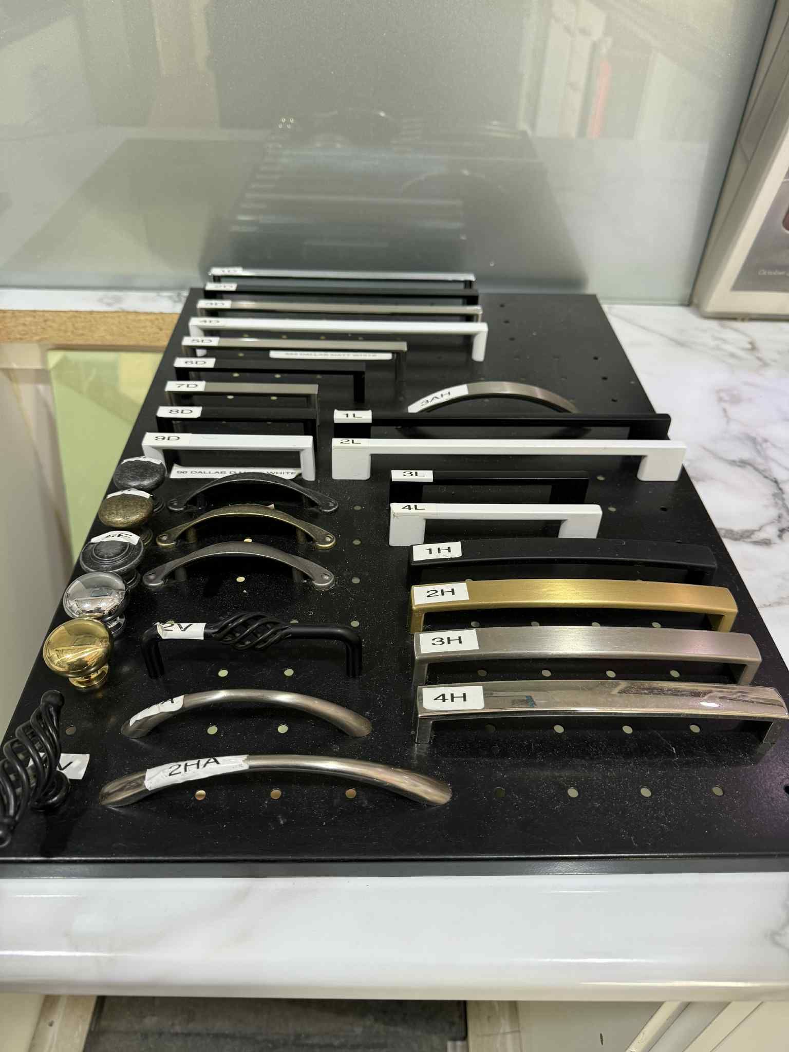 Cabinet handle display on a black board with various metallic finishes.