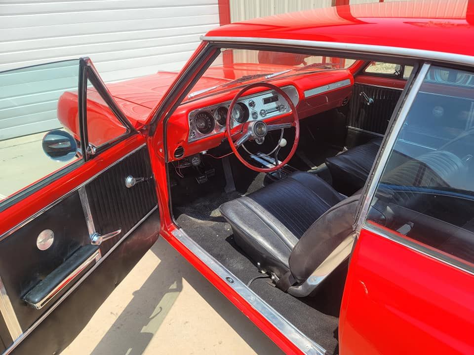 Red classic car with open door, showing red dashboard and black seats inside.