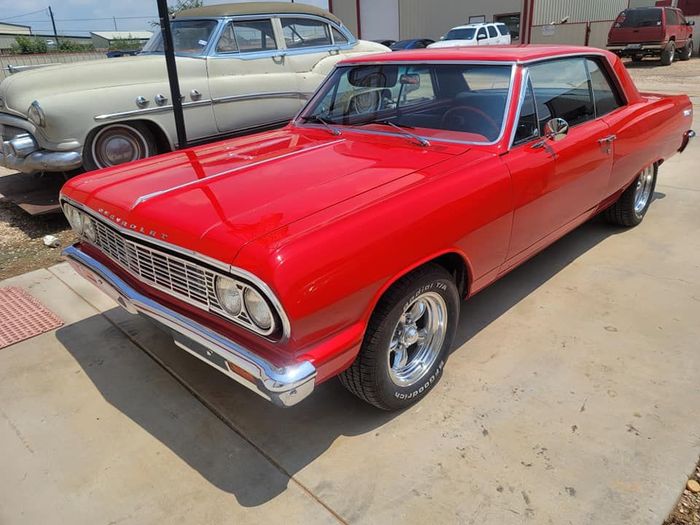 Bright red classic two-door car parked outdoors in a lot
