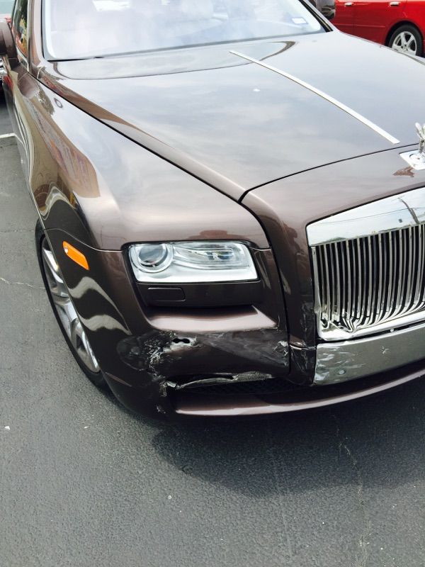 Brown luxury sedan with chrome grille and headlight, close-up on the front end by the road