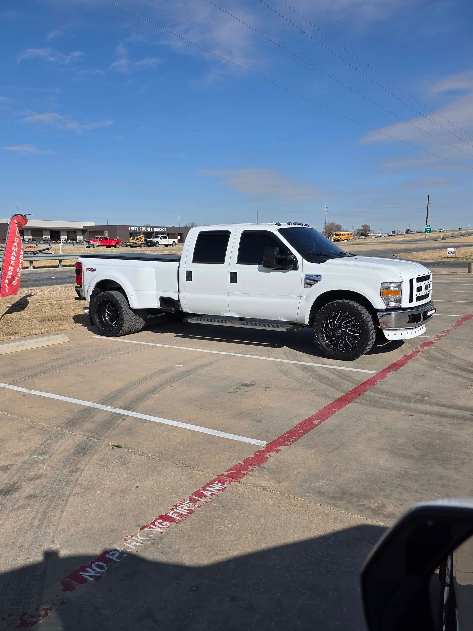 White pickup truck parked in an empty lot under a clear blue sky
