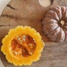 Two small decorative gourds on a rustic wooden surface, one yellow and one pale beige.