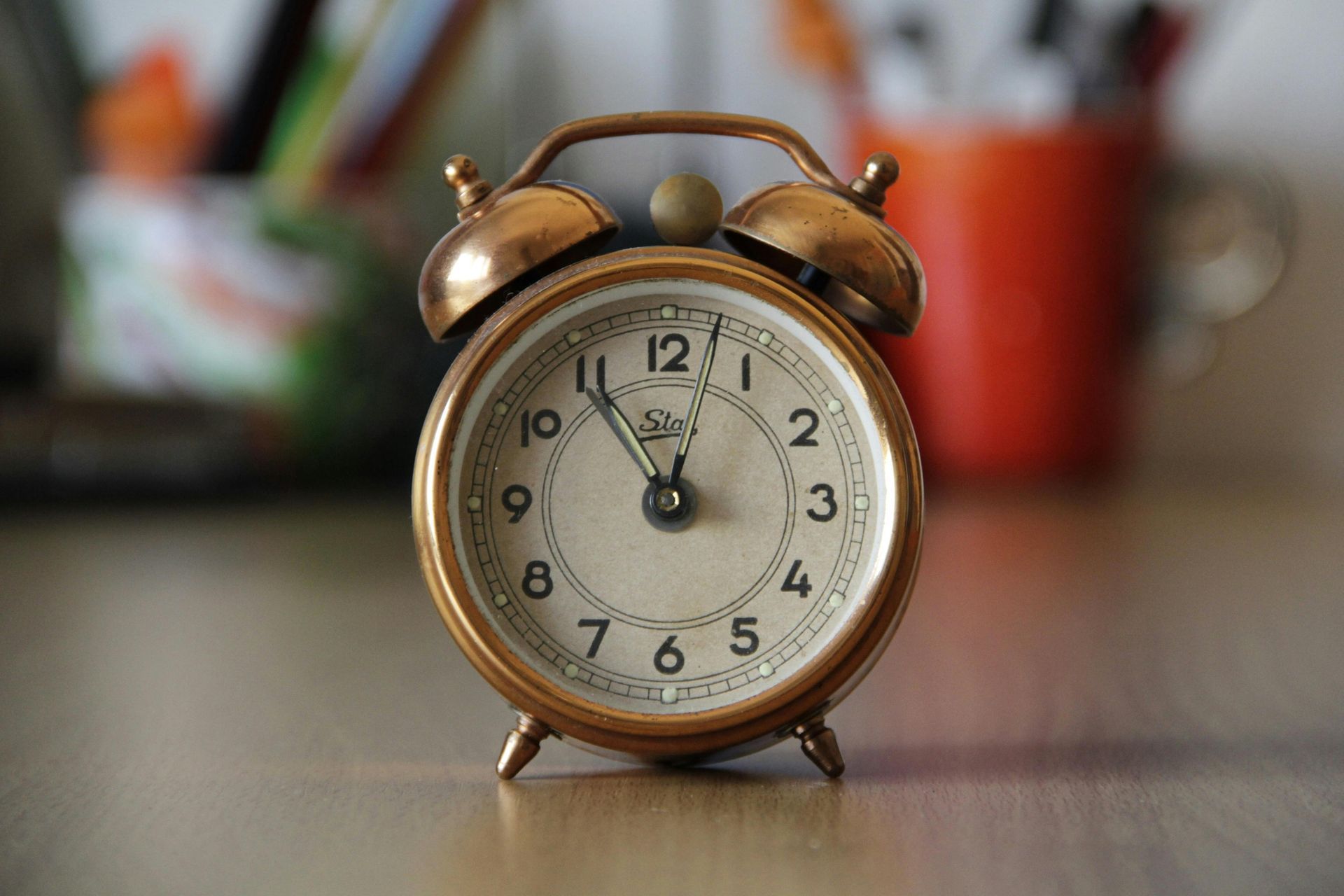 Close-up of a vintage gold alarm clock on a table with a blurred background