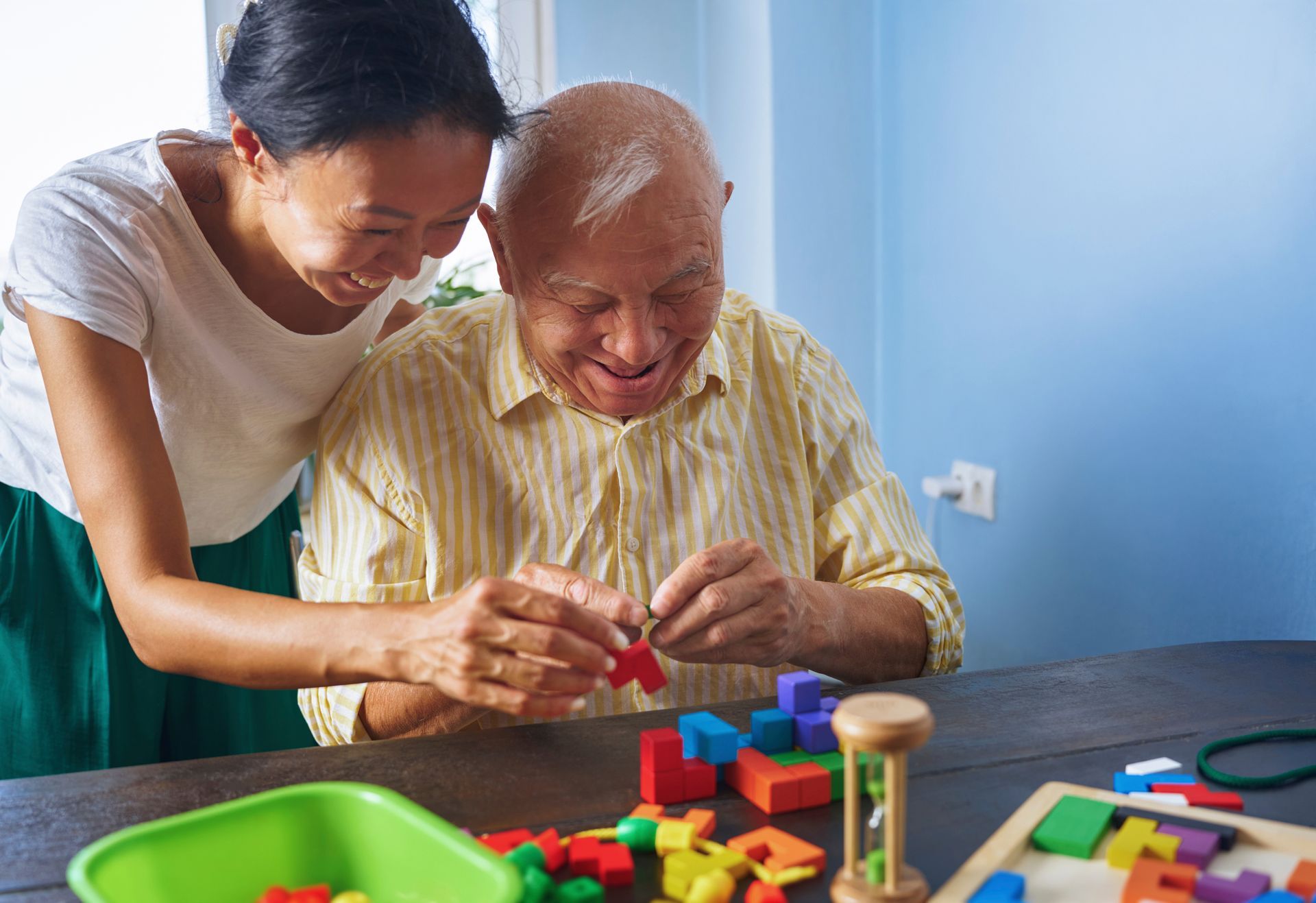 Caregiver showing a tablet to a smiling woman in a bright living room Caregiver showing a tablet to a smiling woman in a bright living room