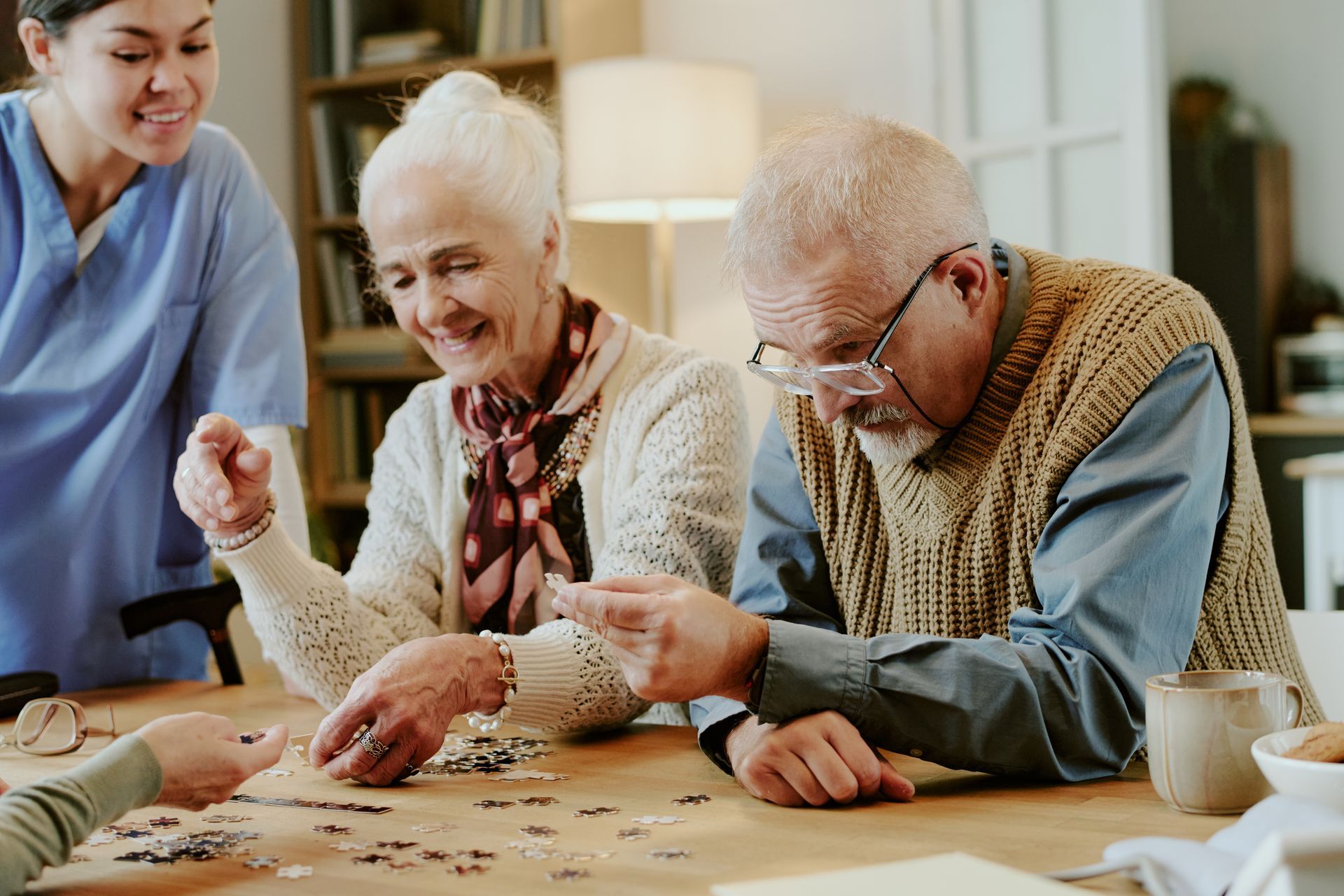 Three people playing a board game at a table, smiling and focused together.