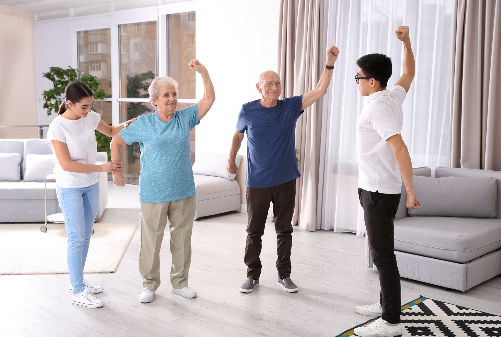 Four people doing a light indoor exercise routine in a bright living room Four people doing a light indoor exercise routine in a bright living room