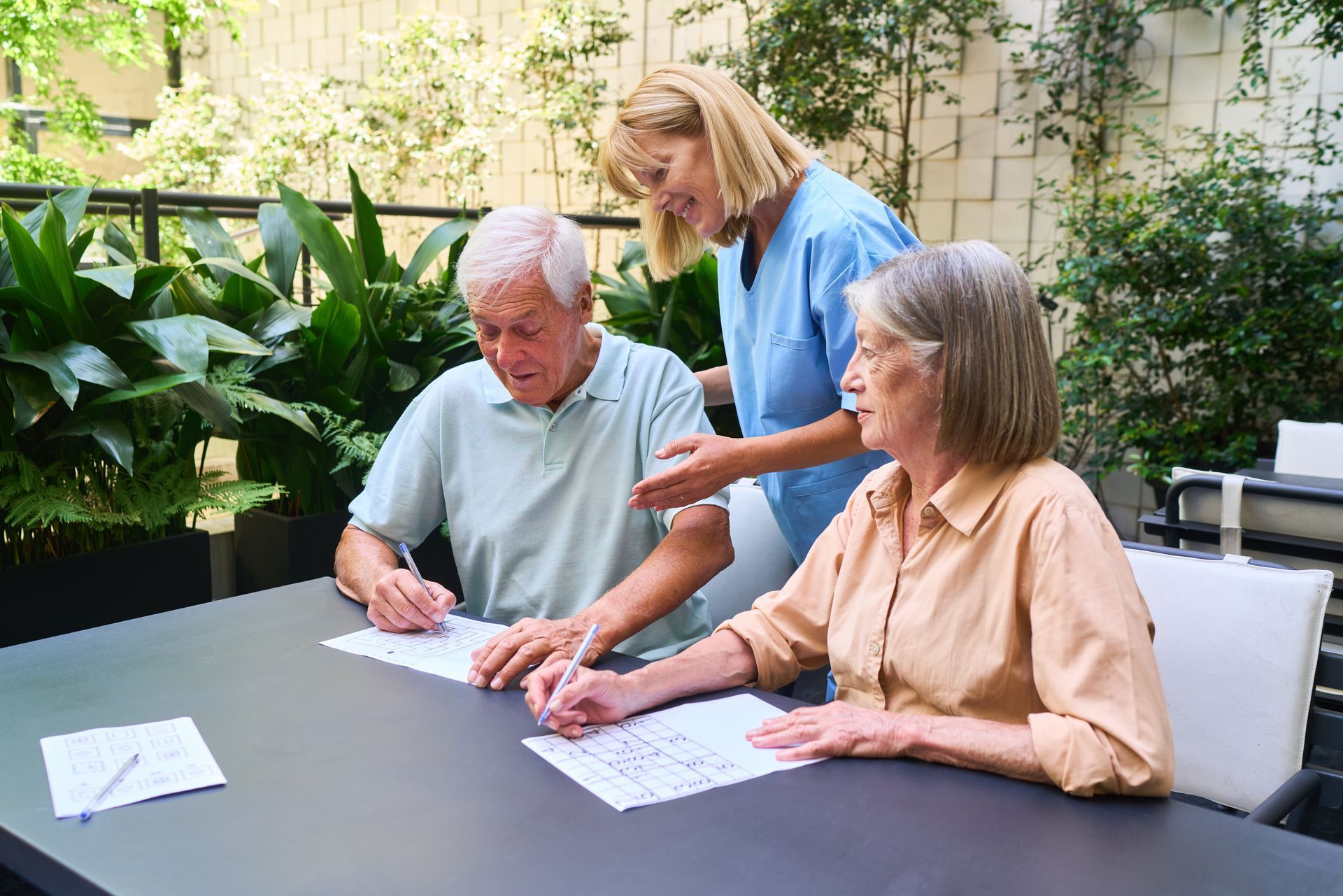 Three people reviewing documents at an outdoor table in a garden courtyard