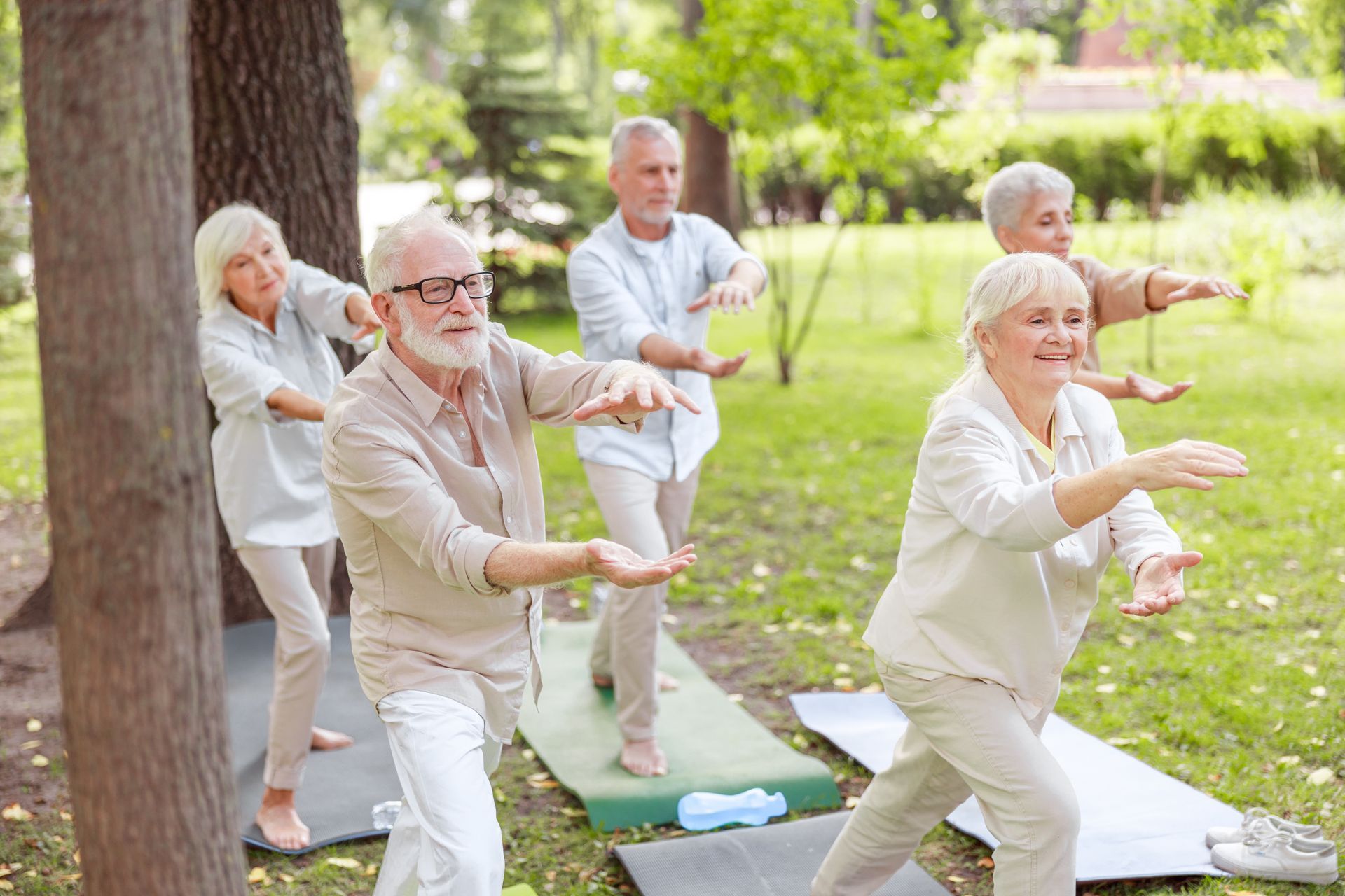 Older adults exercising outdoors on yoga mats in a sunny park