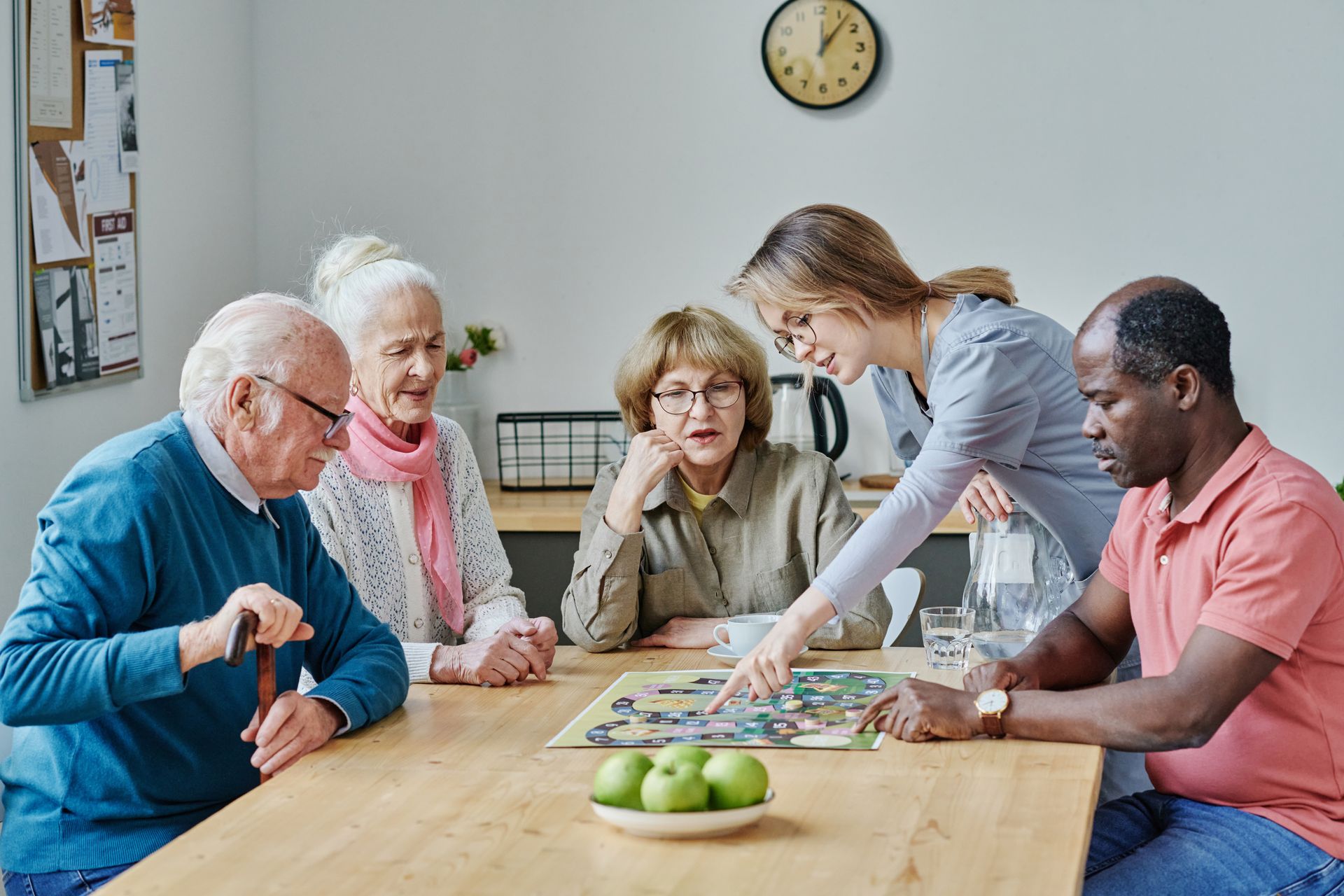 People gathered around a table playing a board game in a bright room People gathered around a table playing a board game in a bright room