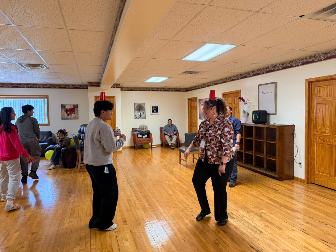 Therapist helping a seated man exercise with yellow dumbbells in a bright room Therapist helping a seated man exercise with yellow dumbbells in a bright room