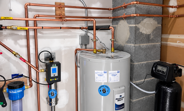 Utility room with water heater, copper pipes, blue filtration unit, and black expansion tank.