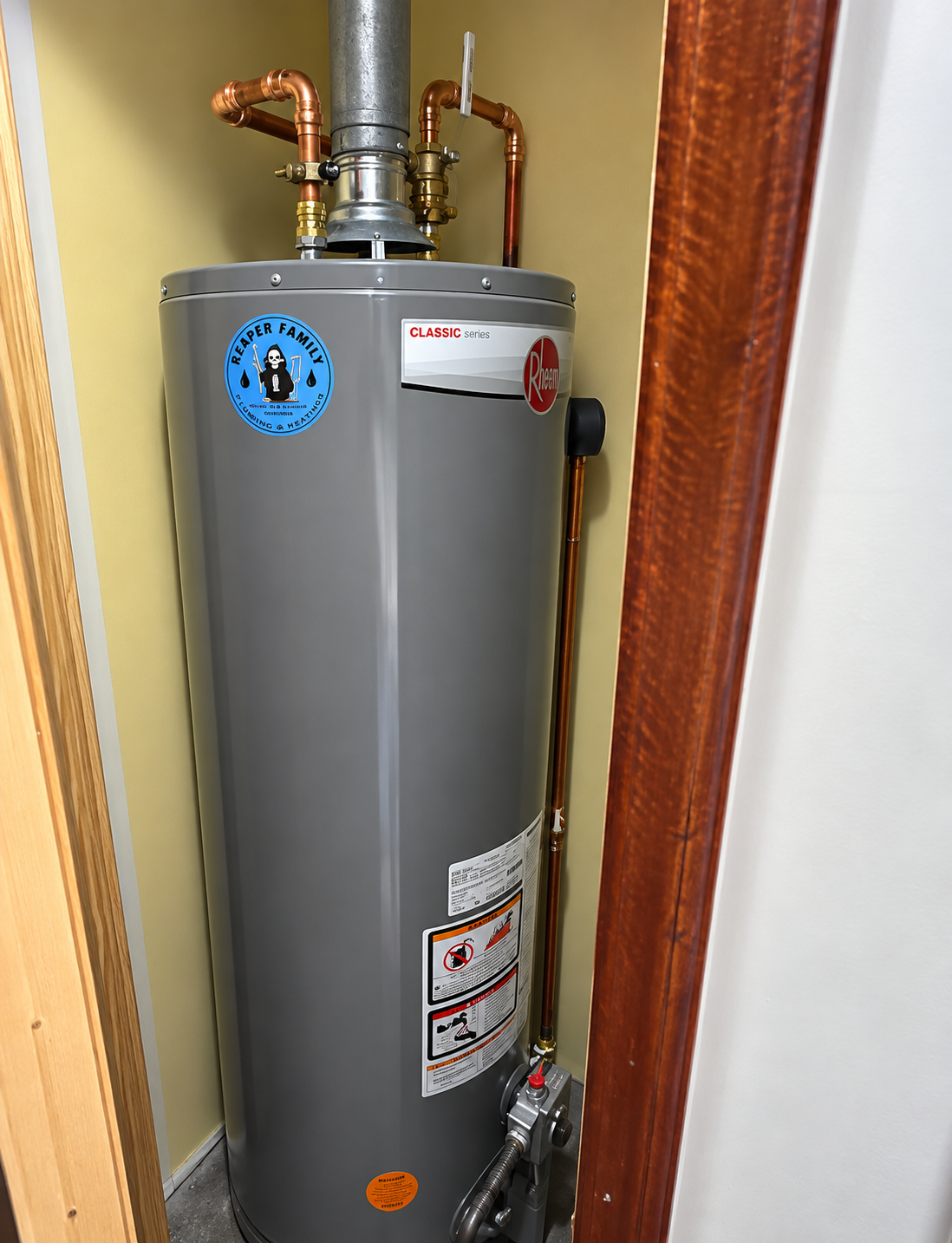 Gray water heater in a narrow utility closet with copper pipes and warning labels