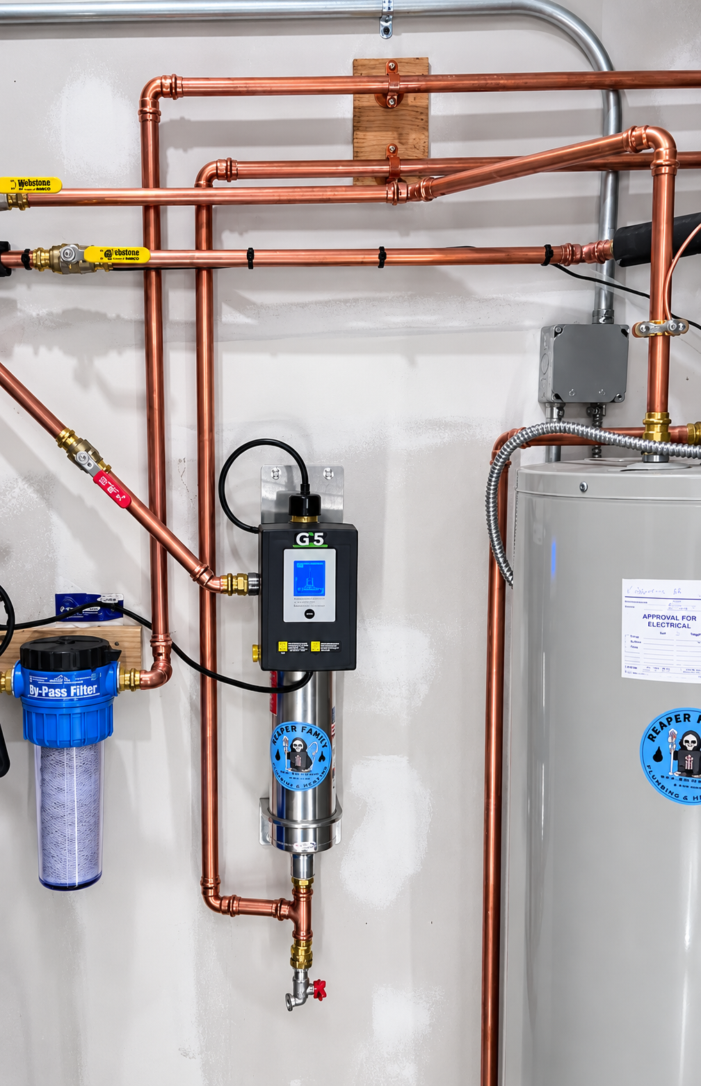 Copper plumbing and water treatment equipment mounted on a wall, with a large tank and blue filter cartridge.
