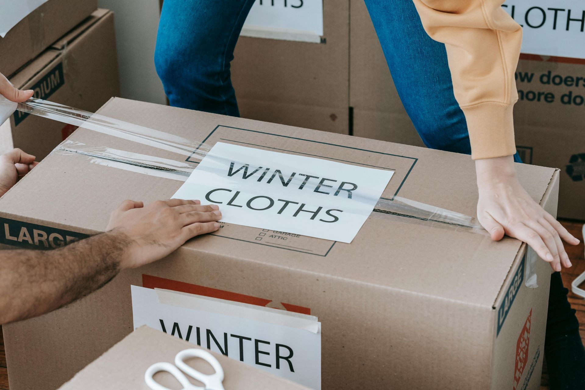 putting tape across a box labeled winter clothes