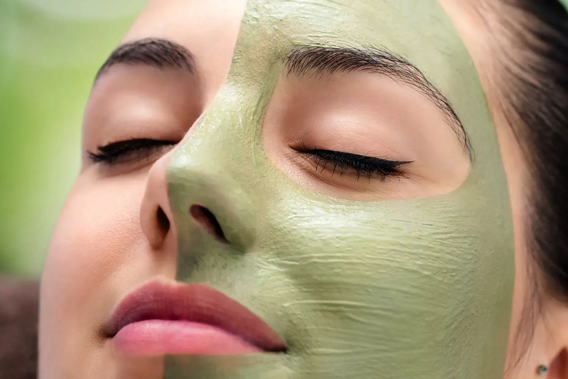 A woman is wearing a green clay mask on her face.