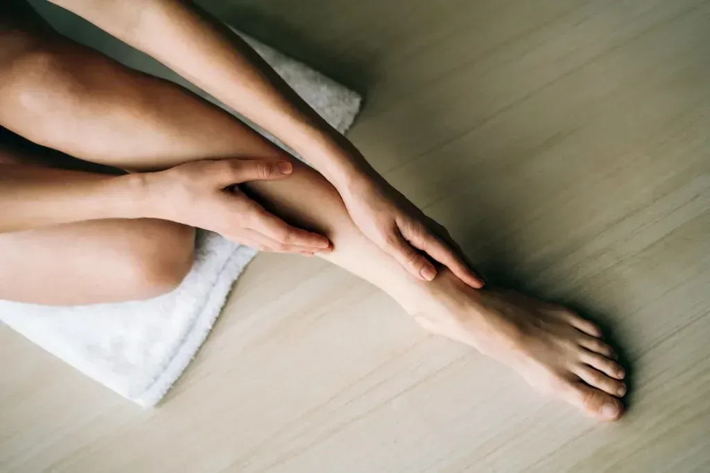 A woman is sitting on the floor with her legs crossed and her hands on her legs.