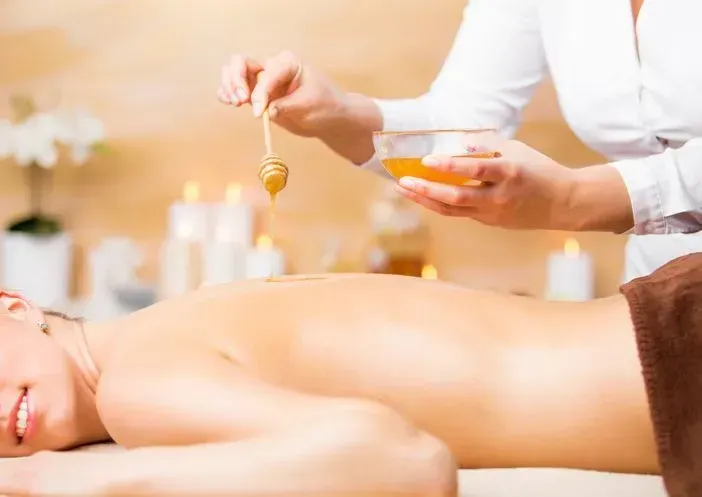 A woman is applying honey to a man 's back at a spa.