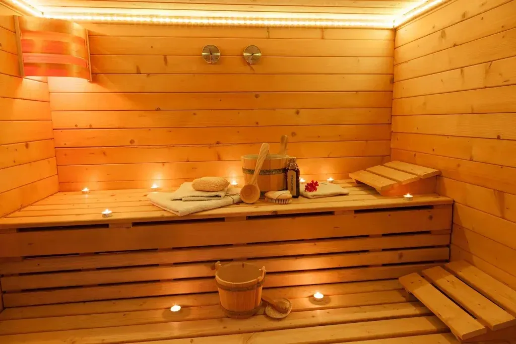 A wooden sauna with a bucket and candles on the floor.