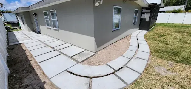 Exterior view of a house with a curved stone walkway and a grassy yard.