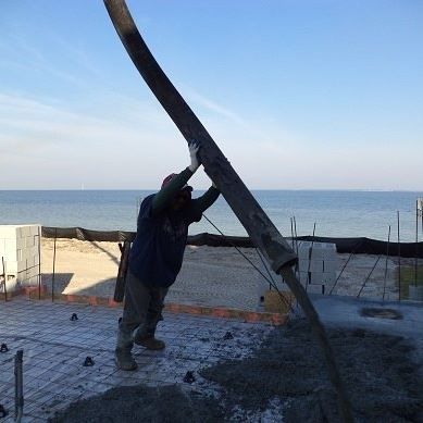 Construction worker pours concrete with a hose on a concrete form, ocean background. Construction worker pours concrete with a hose on a concrete form, ocean background.