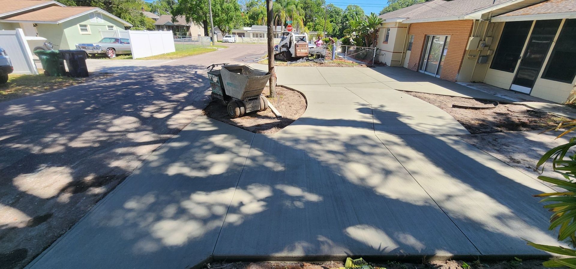 Concrete driveway and yard with shadows from tree. House in background. Concrete driveway and yard with shadows from tree. House in background.