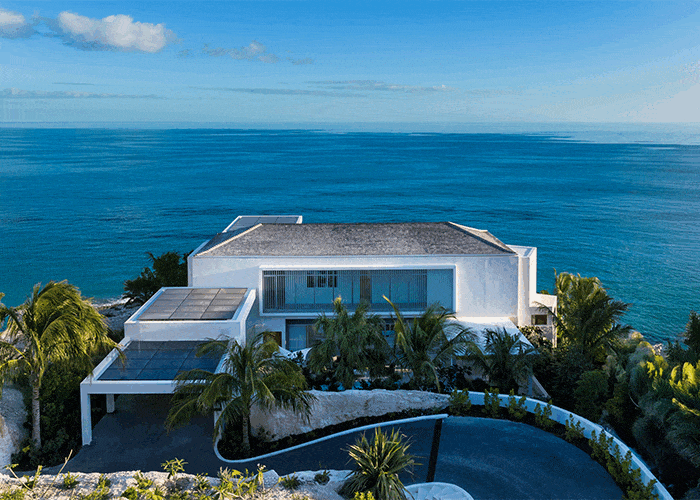 A large swimming pool is surrounded by lawn chairs and umbrellas