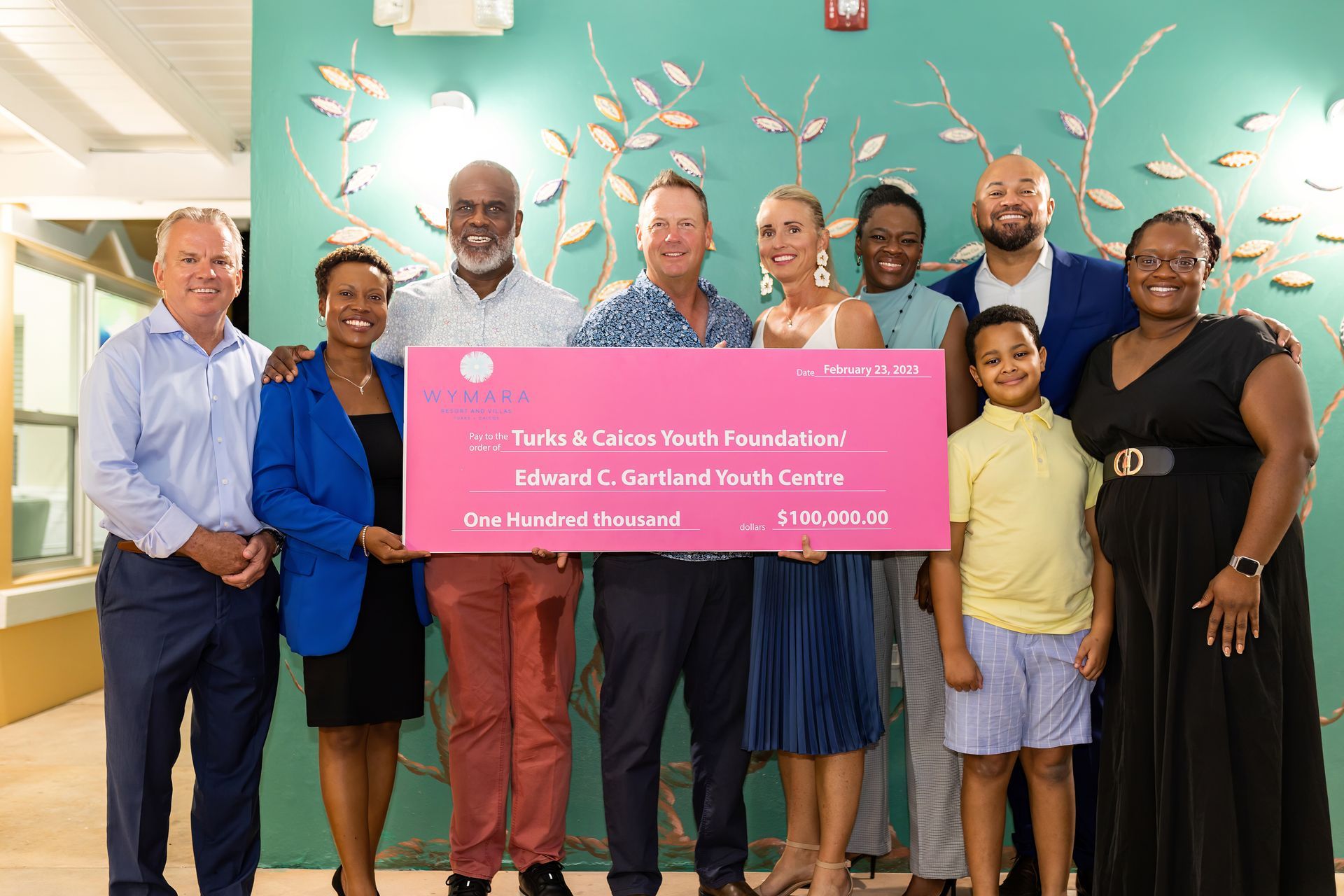 A group of people holding a large pink check