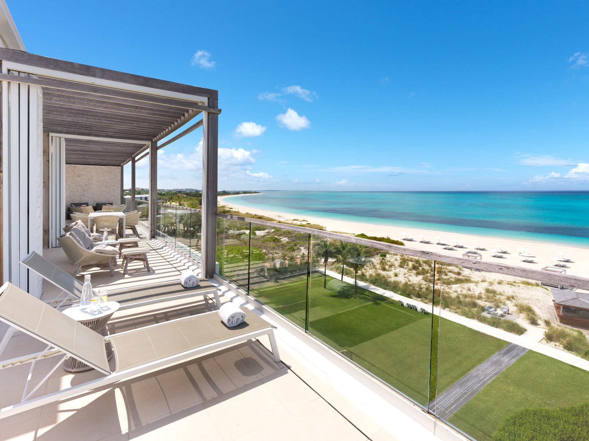 Two chairs and a table under a pergola overlooking the ocean