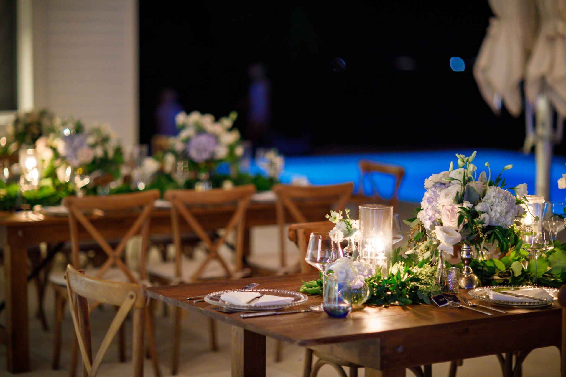 A table with flowers and candles on it in front of a pool