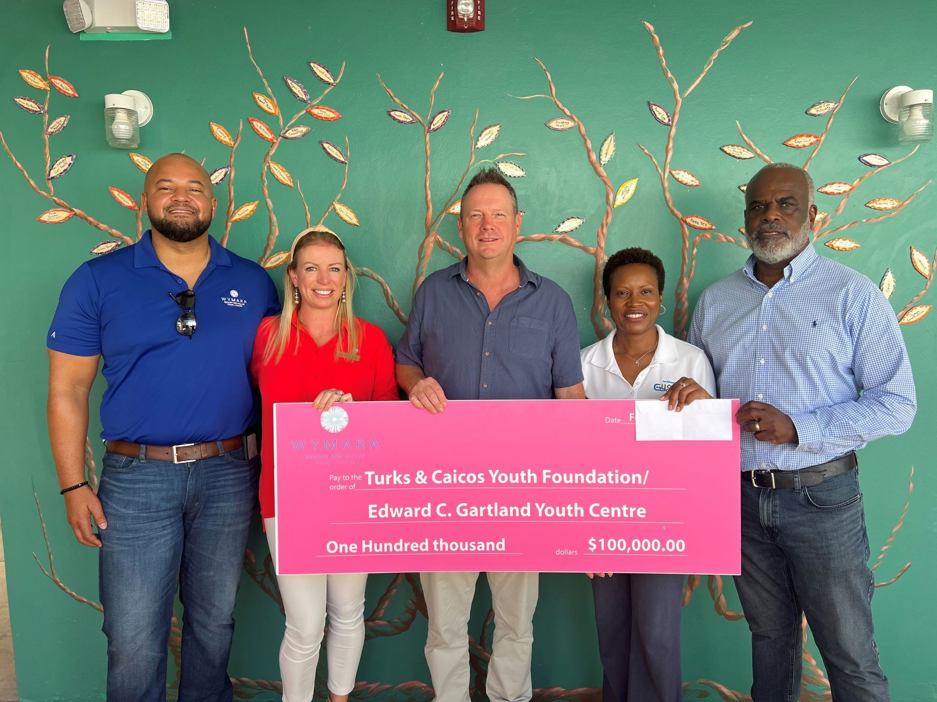A group of people holding a large pink check that says youth foundation