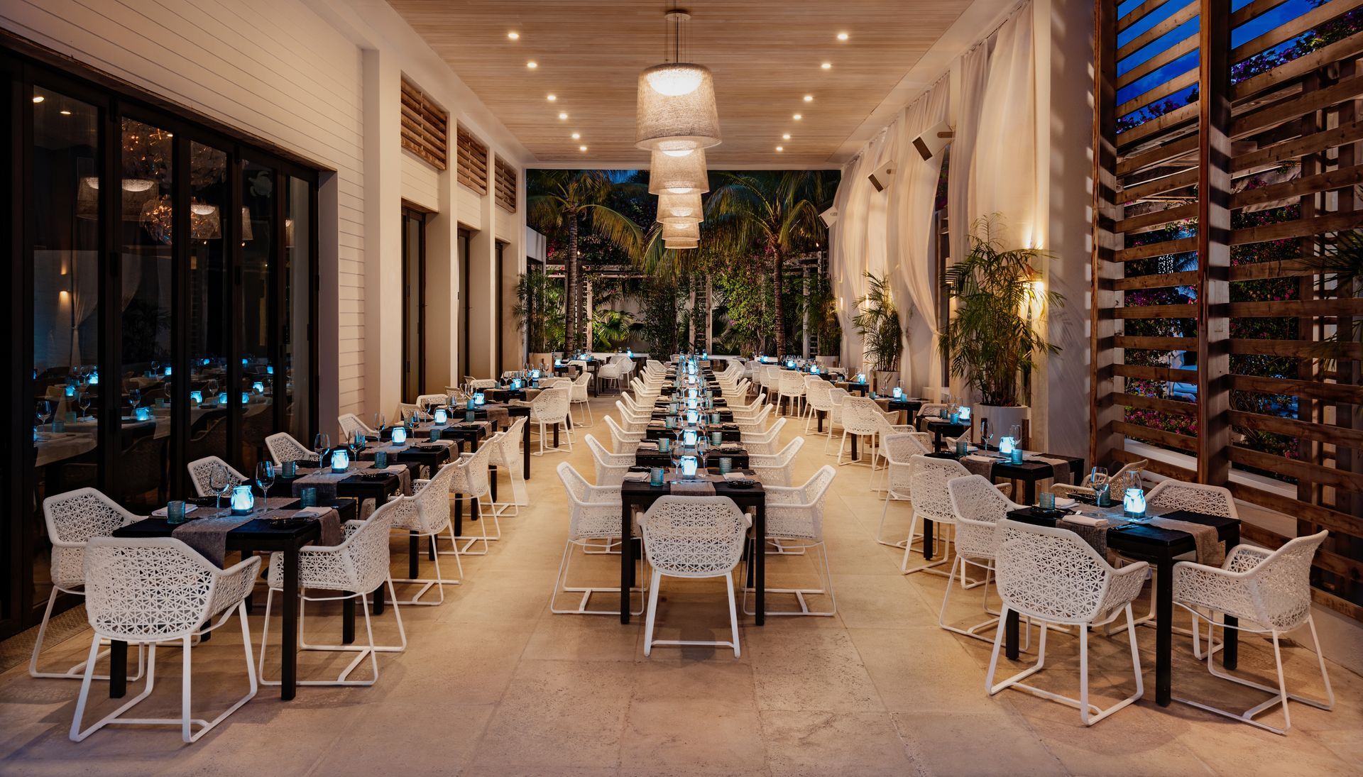 A large dining room with tables and chairs and a chandelier