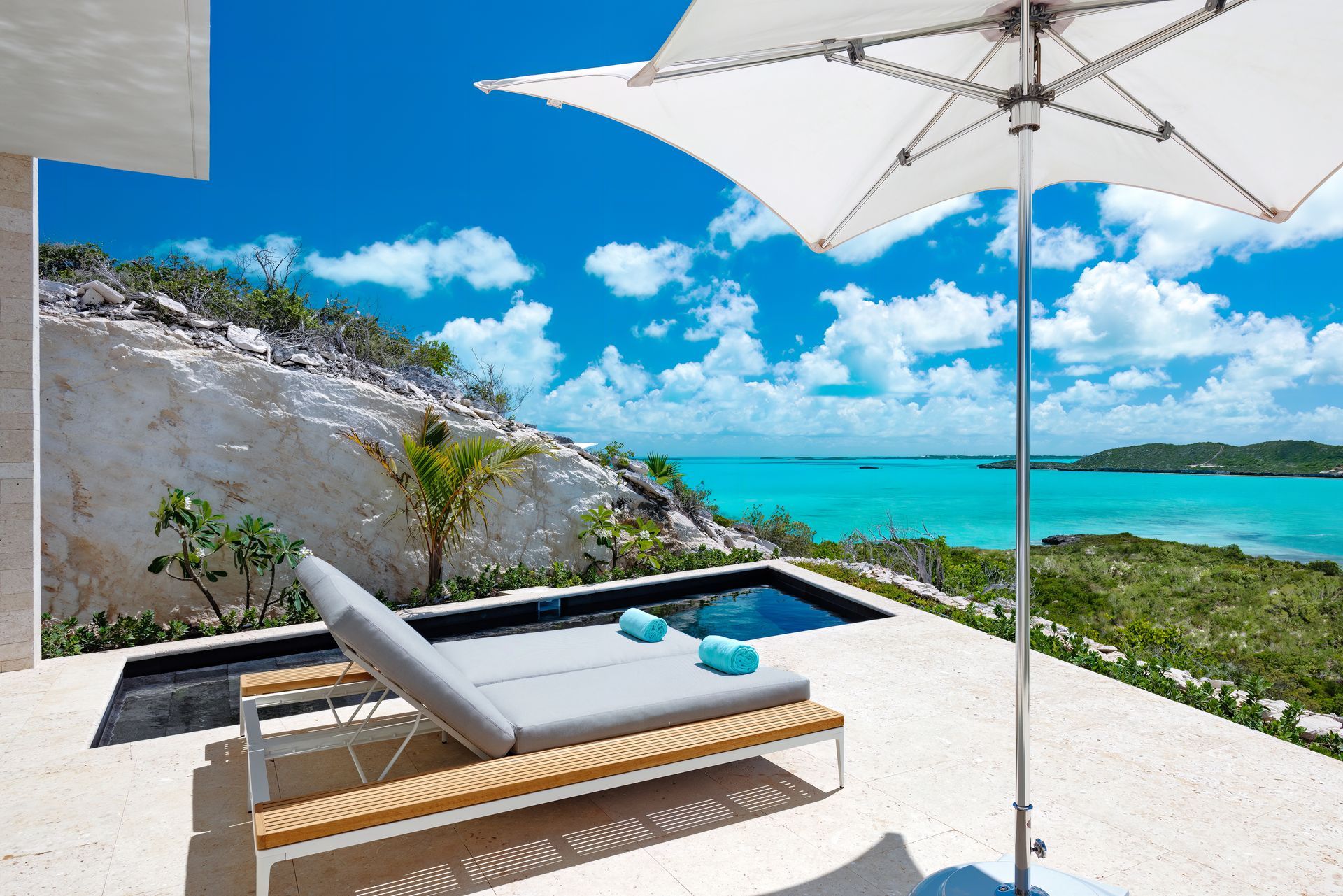 A white umbrella sits on a patio overlooking the ocean