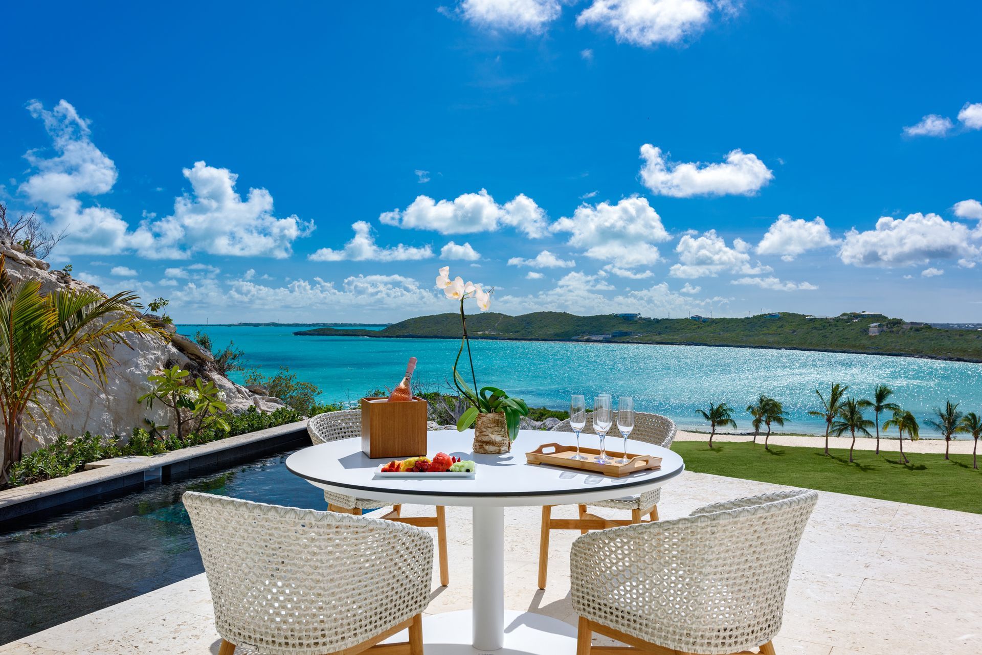 A patio with a table and chairs overlooking the ocean