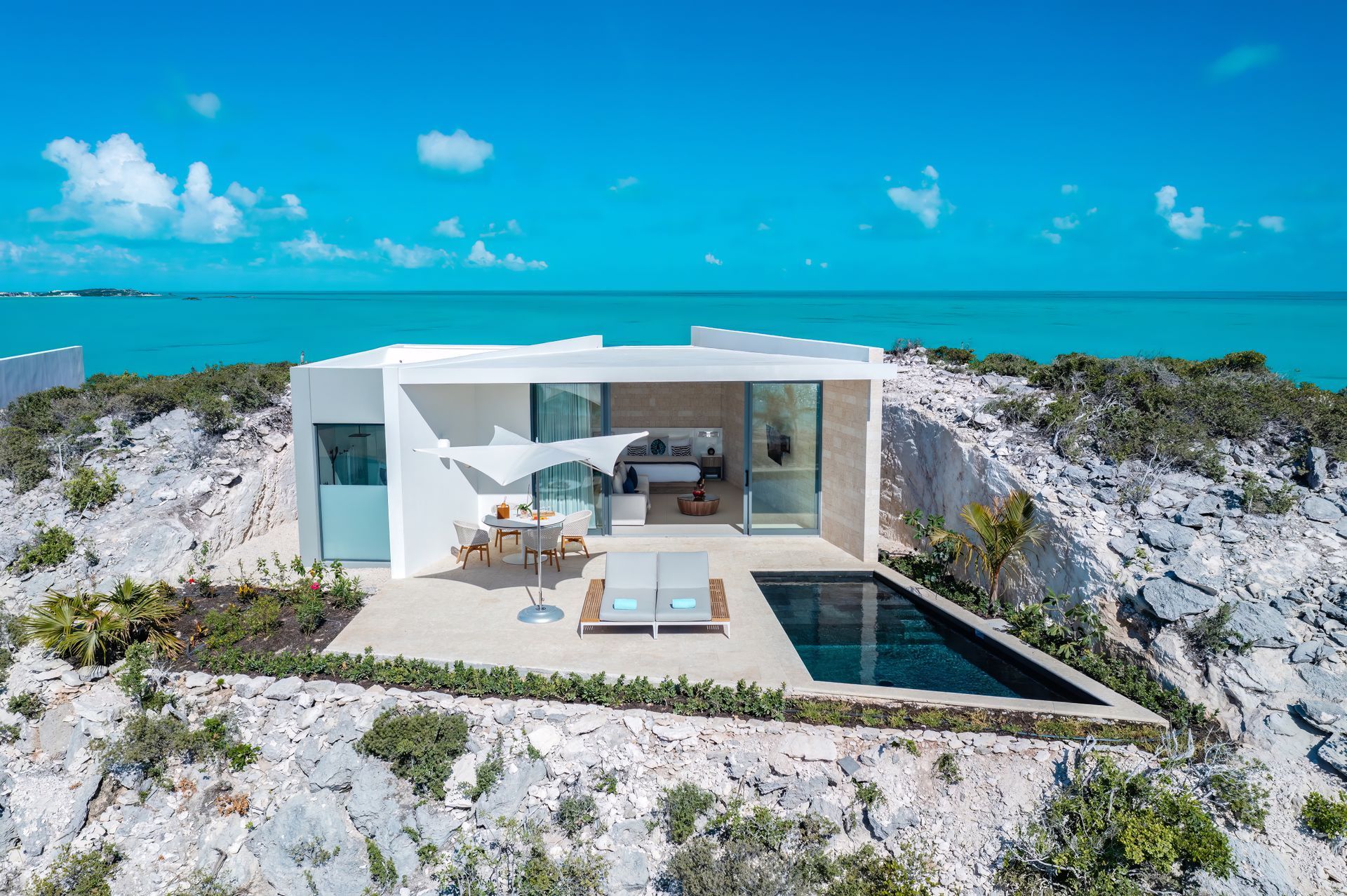 An aerial view of a house with a swimming pool in front of the ocean