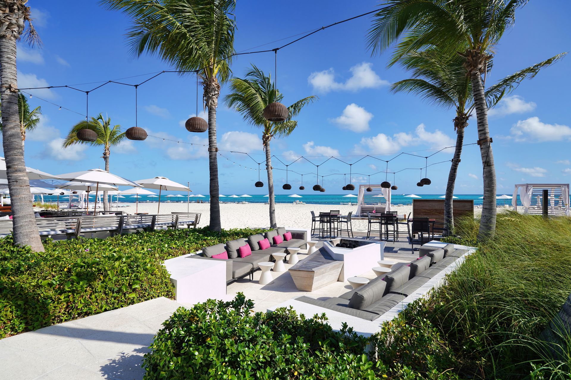 A beach with palm trees and tables and chairs