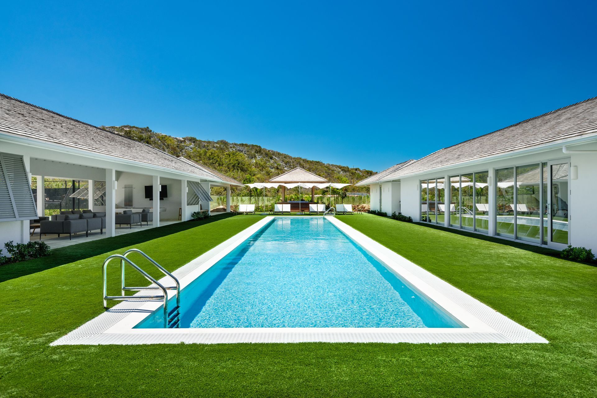 A large swimming pool in the middle of a lush green yard