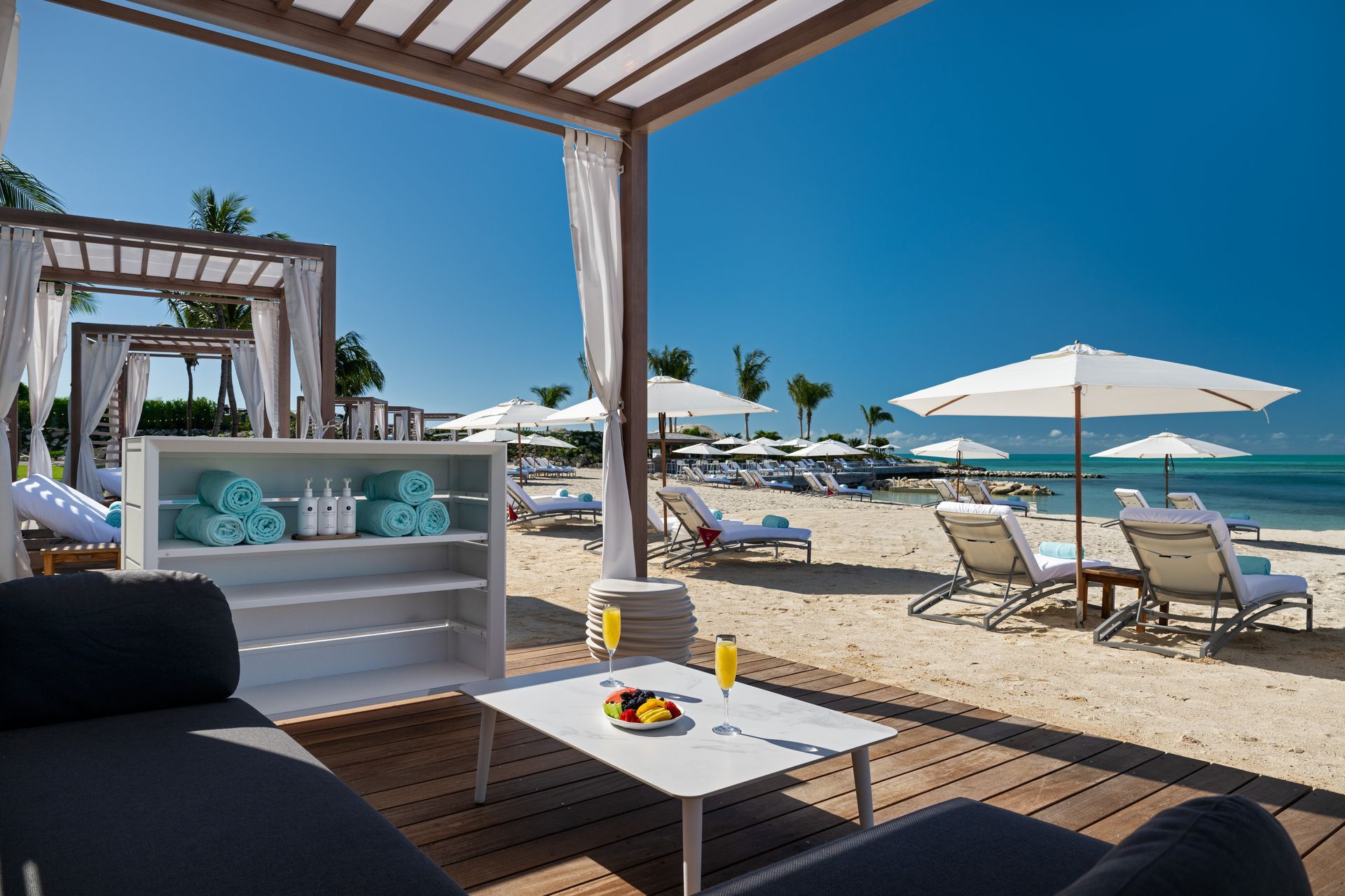 A swimming pool surrounded by chairs and umbrellas on a beach