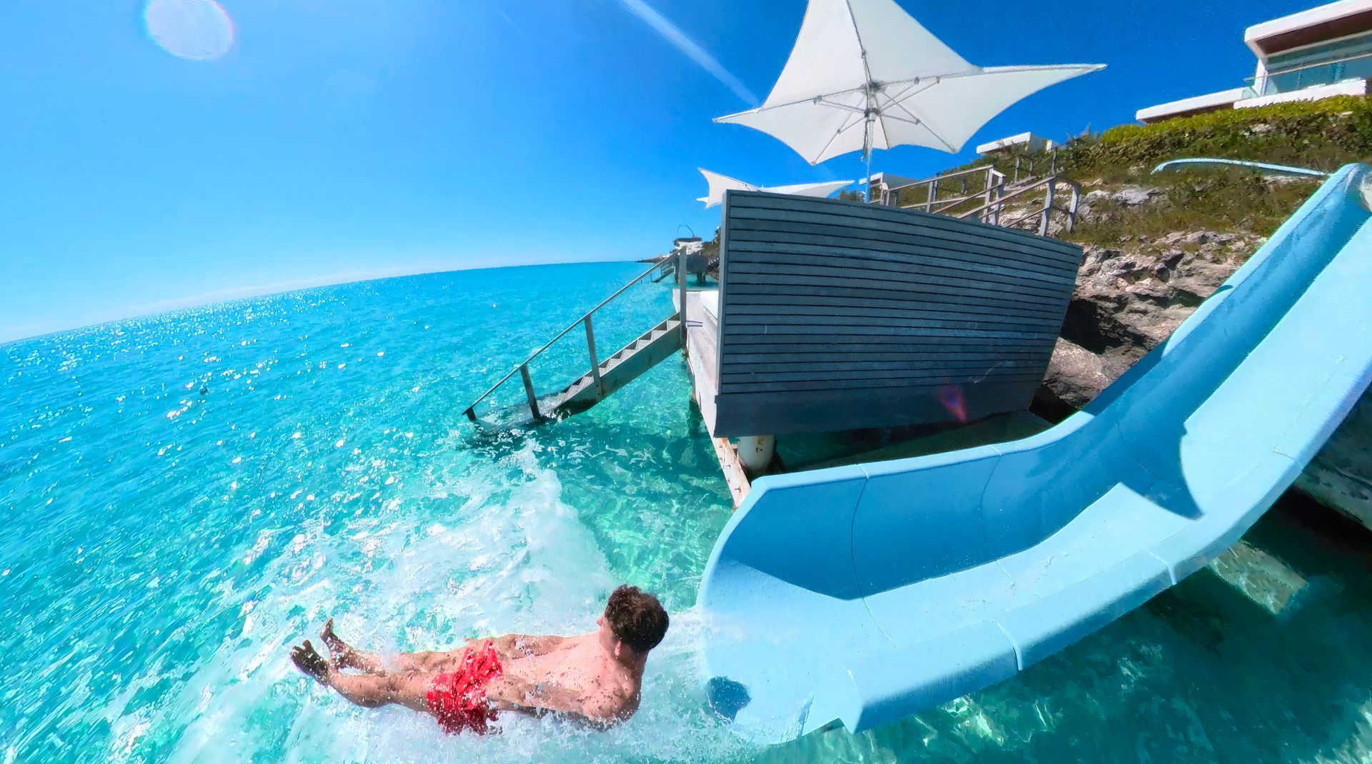 A man is going down a water slide in the ocean