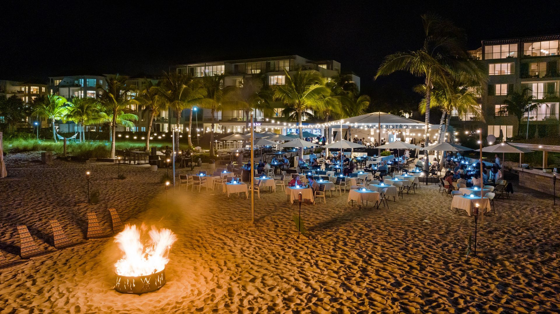 A fire pit is lit up on a beach at night